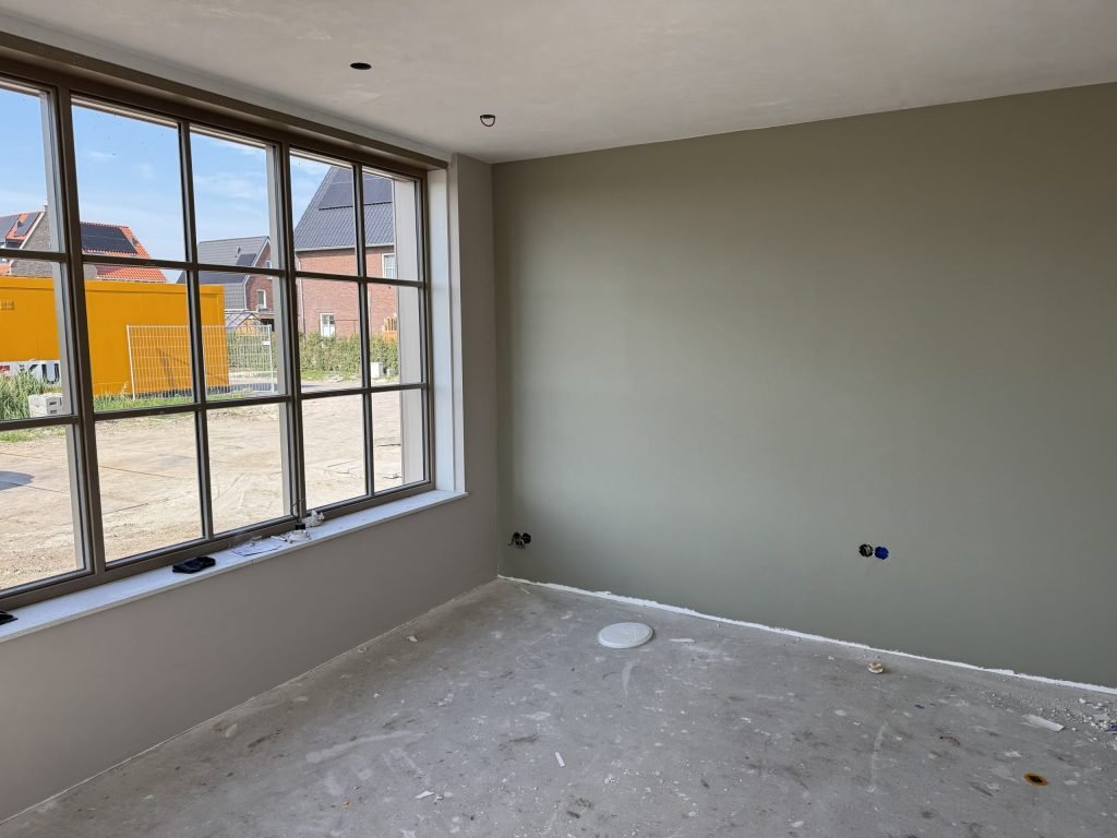 Nieuwe kamer met een groen gesausde wand en een grote raampartij